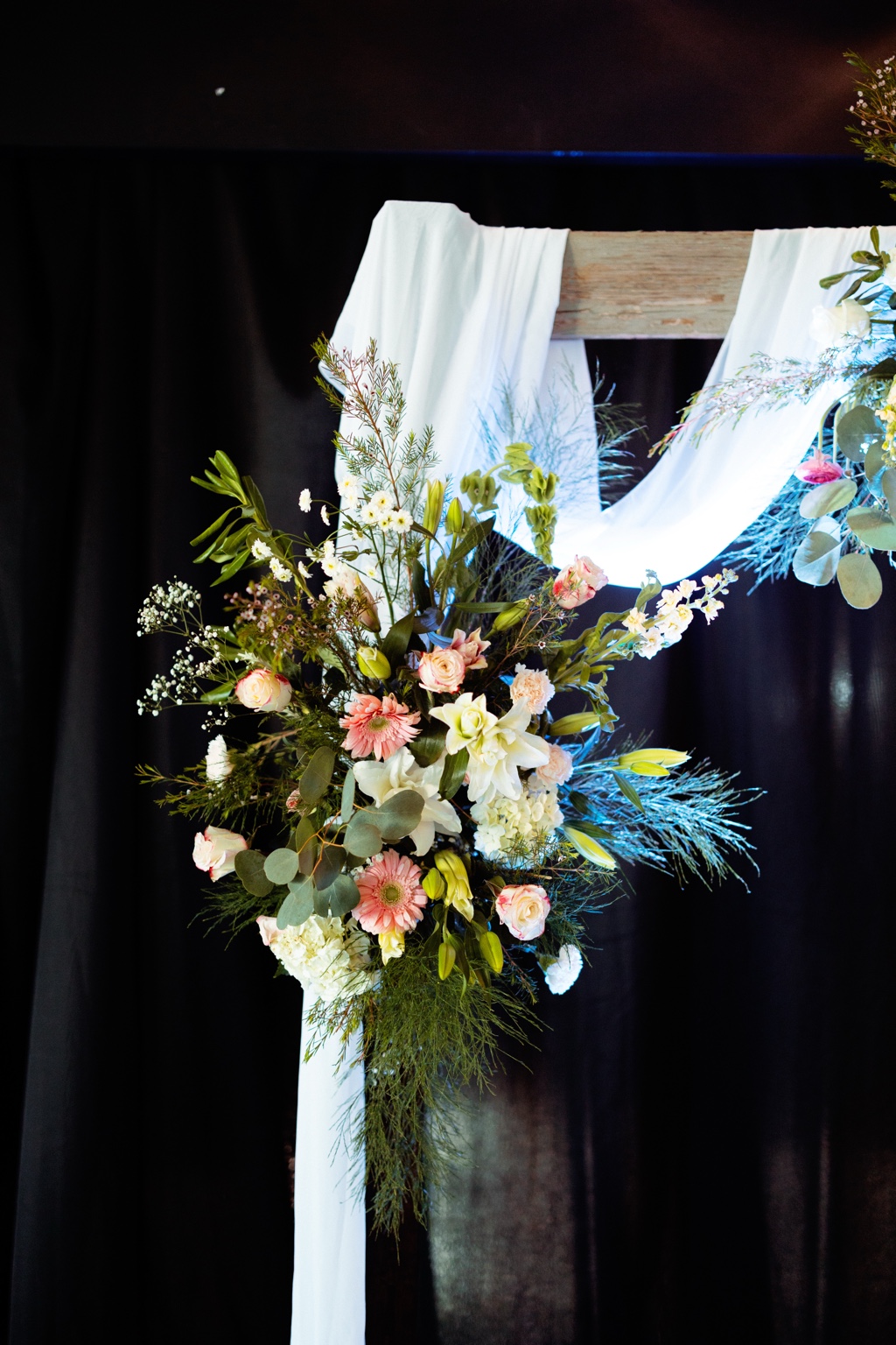 Colorful floral arrangement beside soft white draping