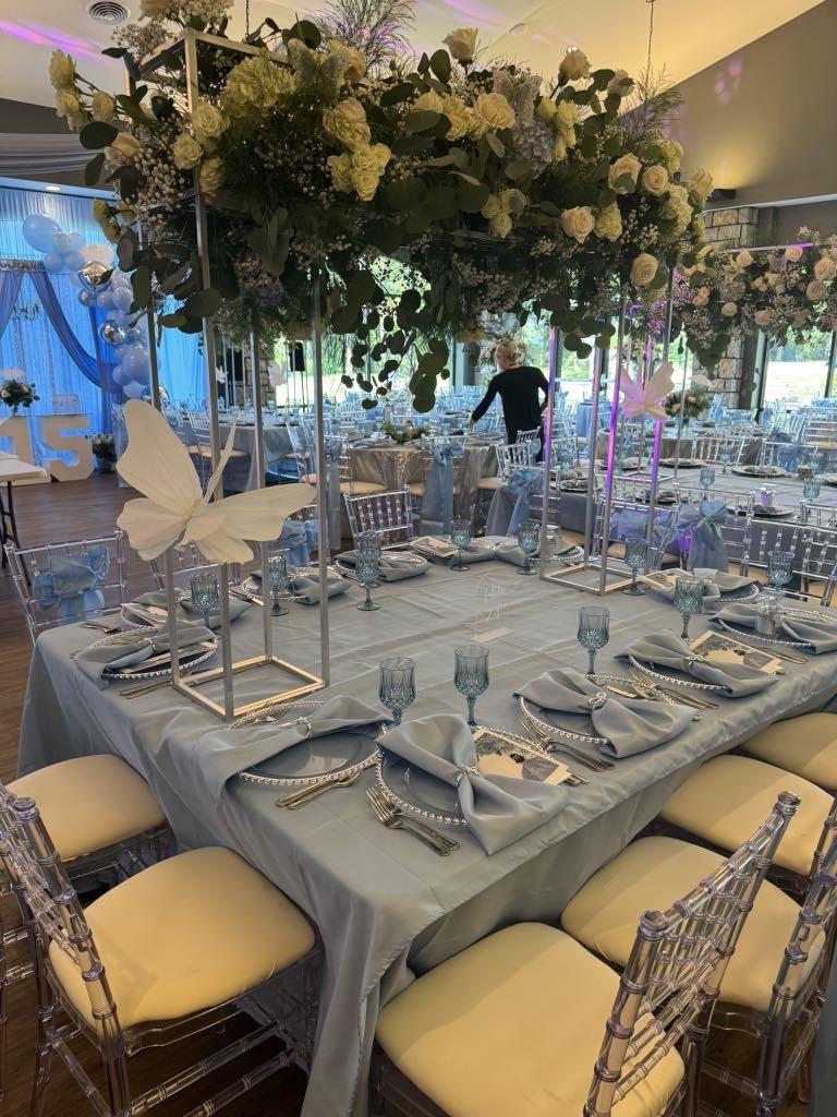 Tall white floral centerpiece above a blue and silver table setting