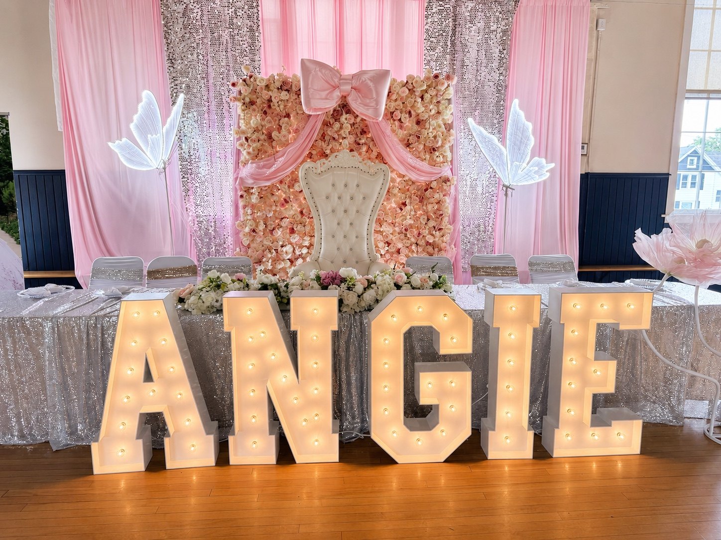 Illuminated ANGIE letters with pink draping and a quinceañera throne