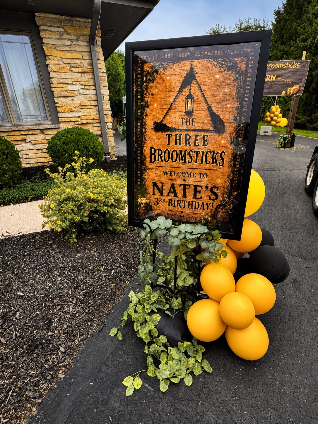 Three Broomsticks welcome sign for Nate’s third birthday with black and yellow balloons