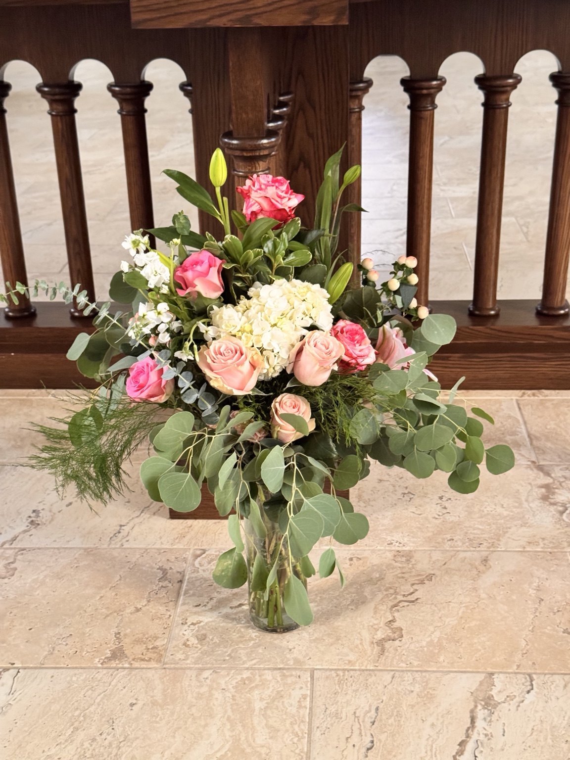 Pink and cream floral arrangement with eucalyptus in a glass vase