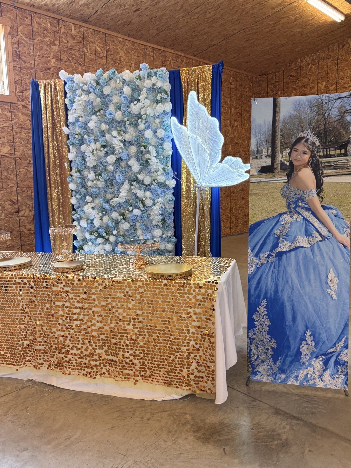 Blue and white floral backdrop with an illuminated butterfly and gold table decor