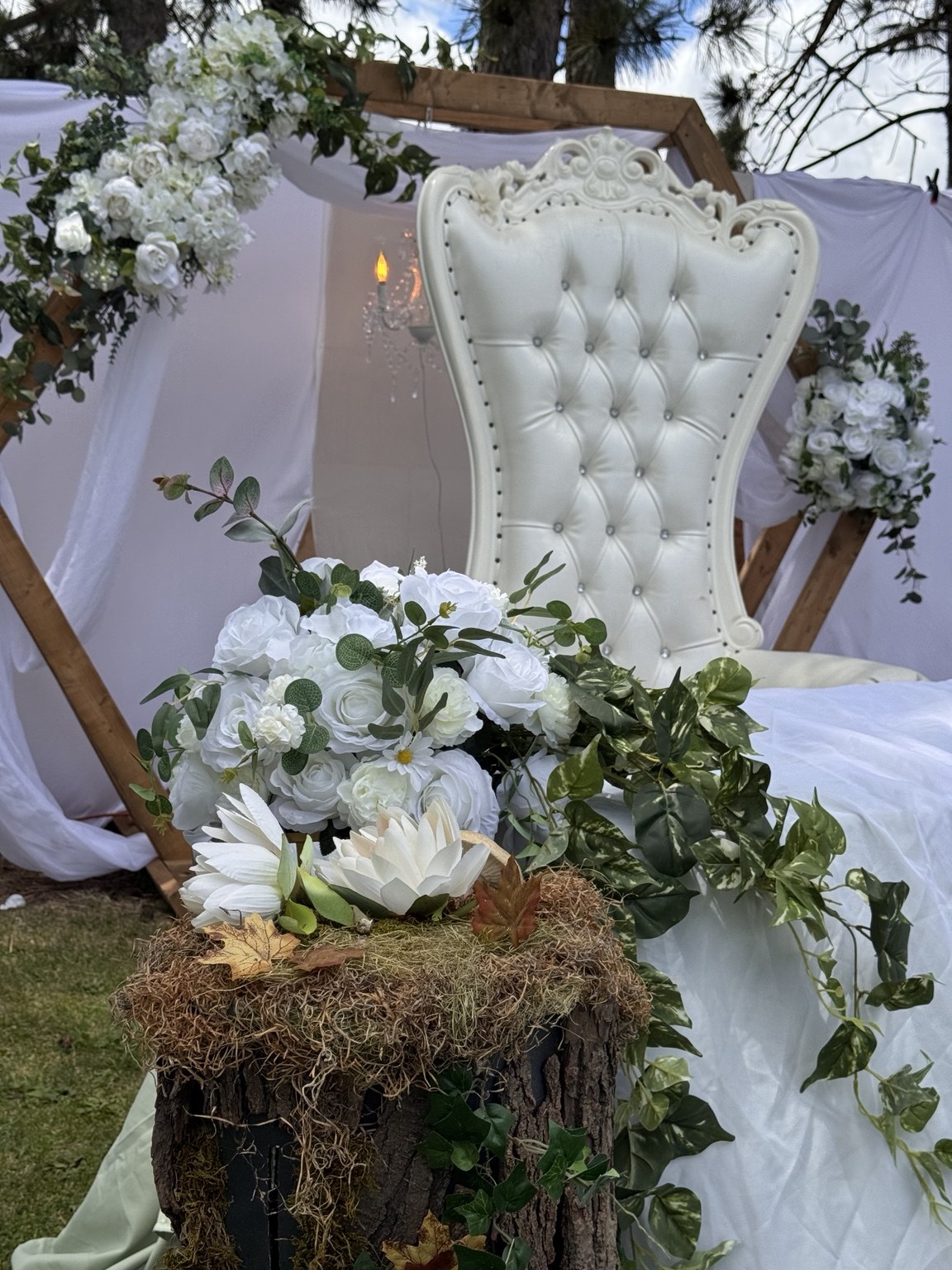White tufted throne surrounded by white flowers and rustic outdoor details