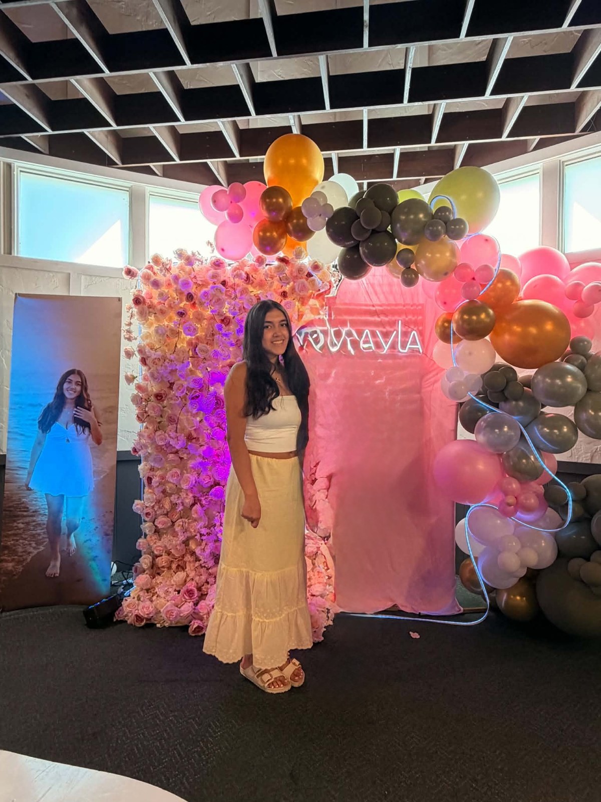 Pink celebration backdrop with colorful balloon garlands and a floral wall