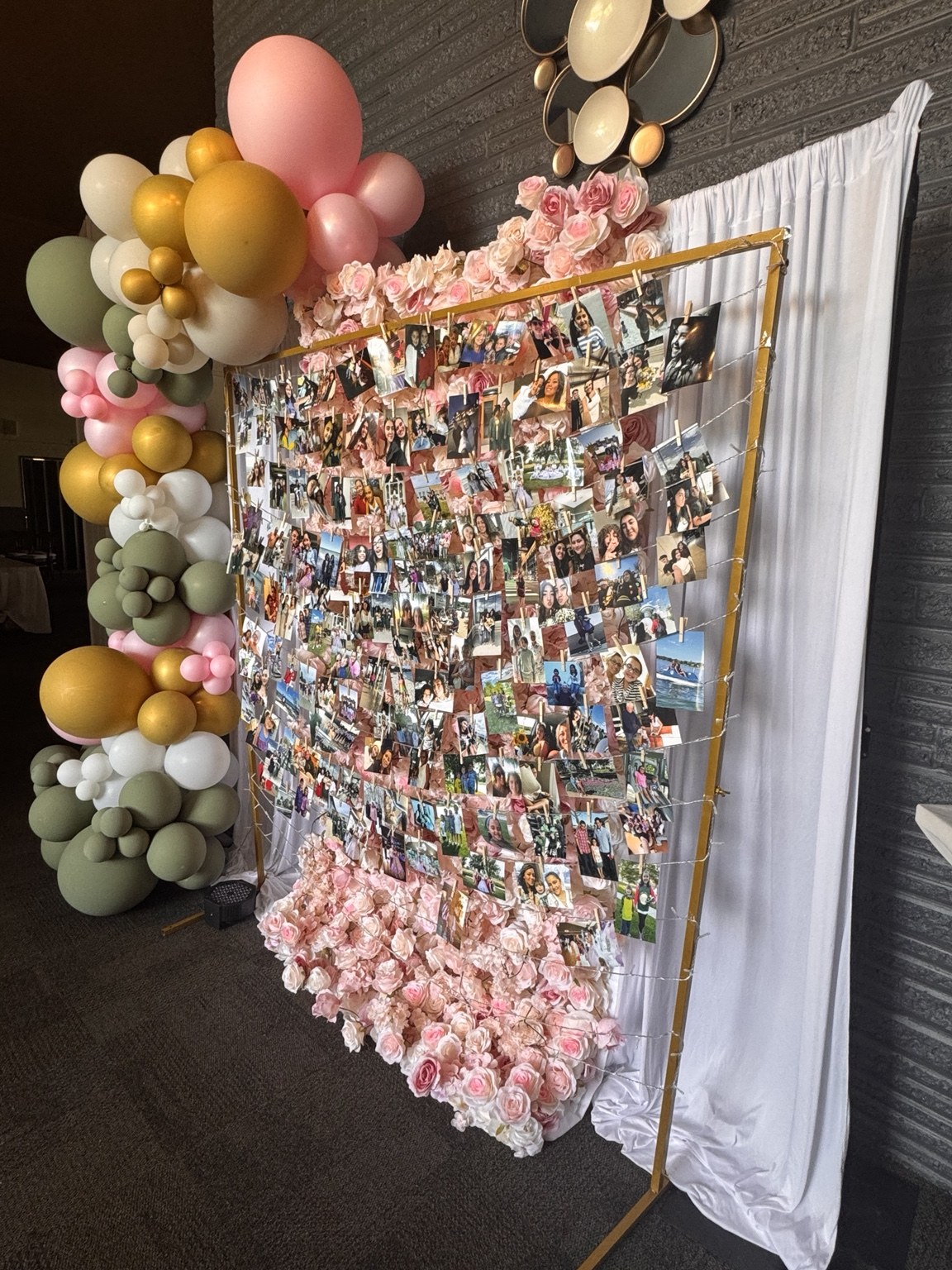 Photo display framed with pink flowers, draping and a colorful balloon garland