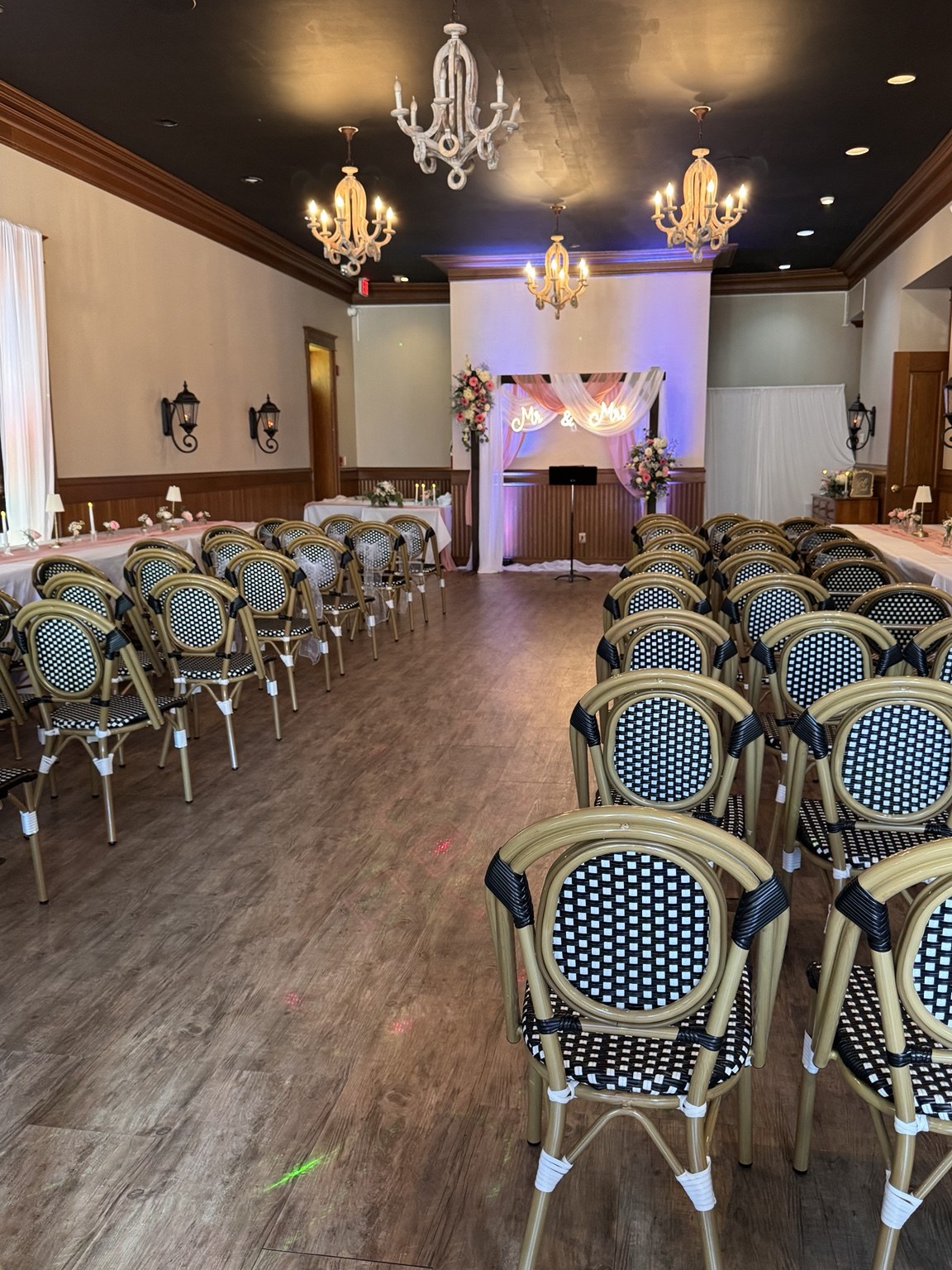 Wedding ceremony room with rows of elegant chairs and a draped floral arch