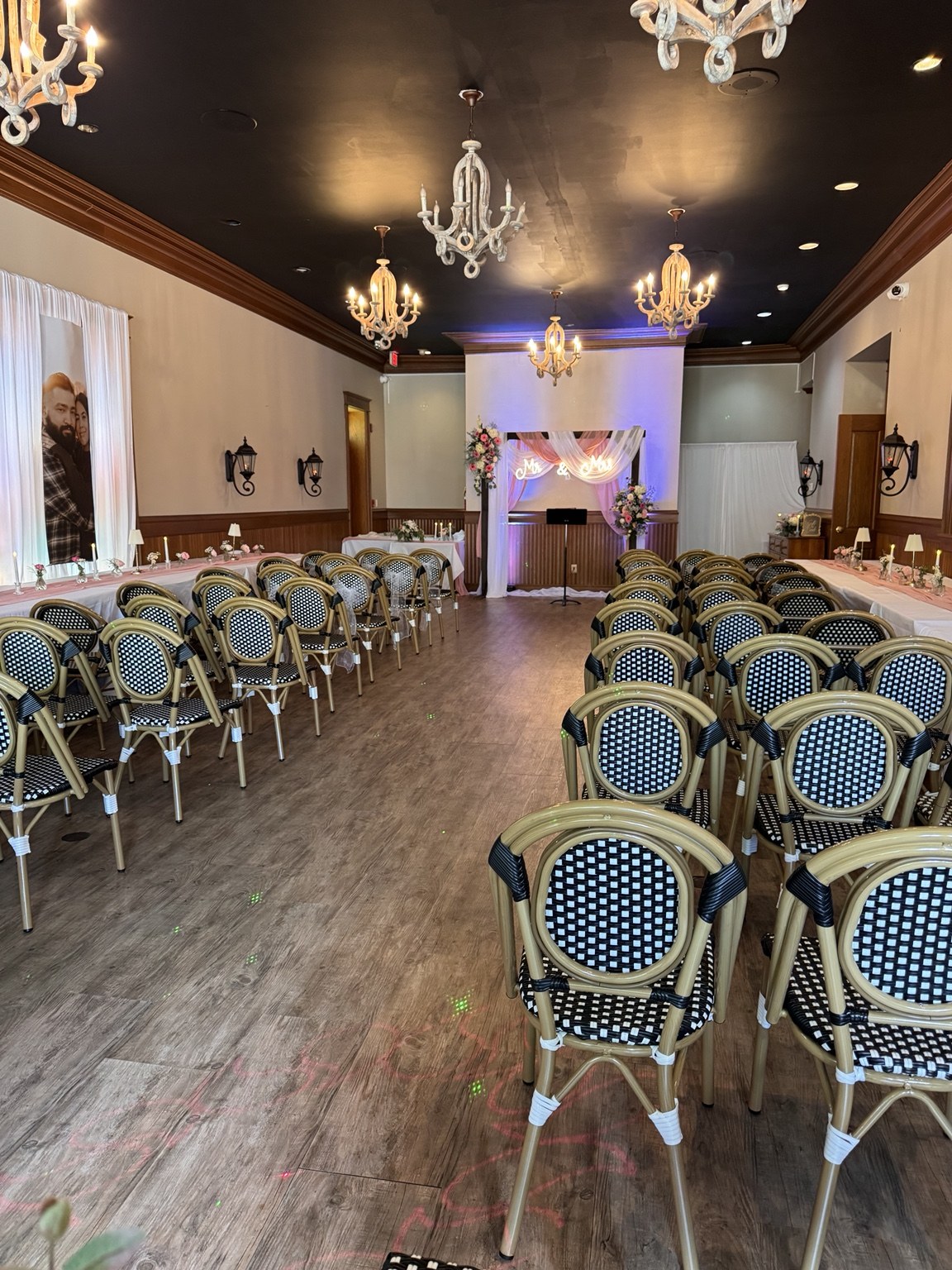 Wedding aisle leading to a floral arch beneath chandeliers