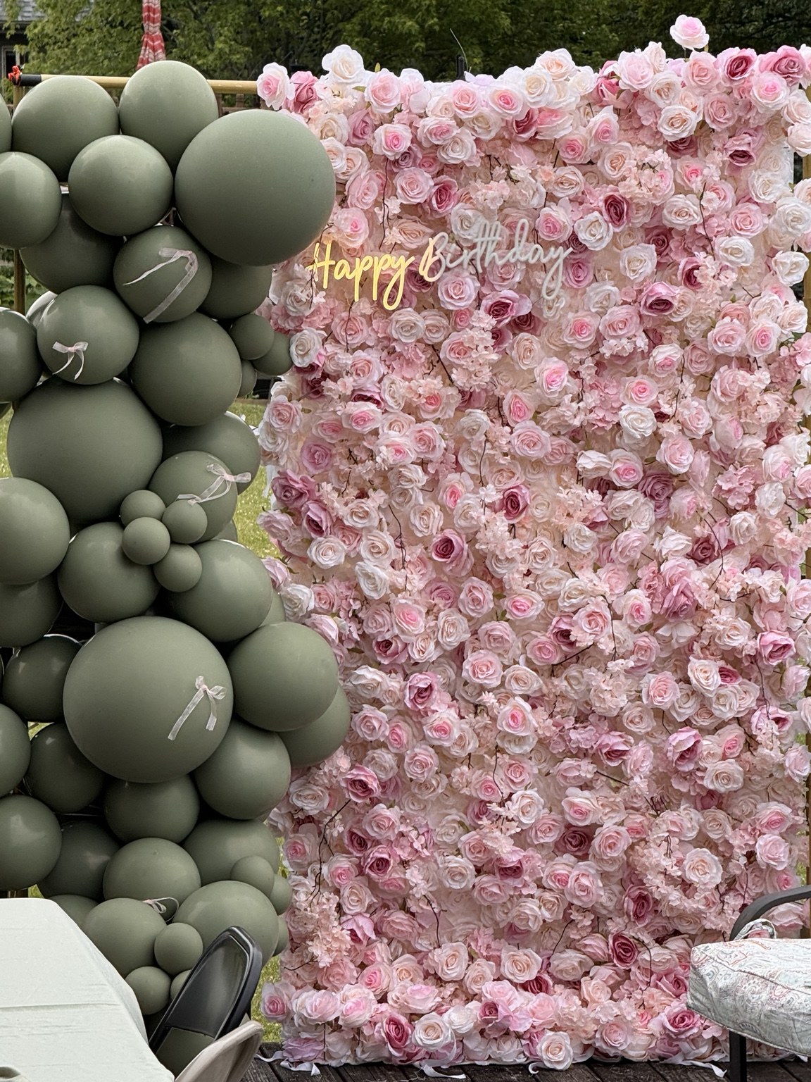 Pink flower wall with a sage green organic balloon garland