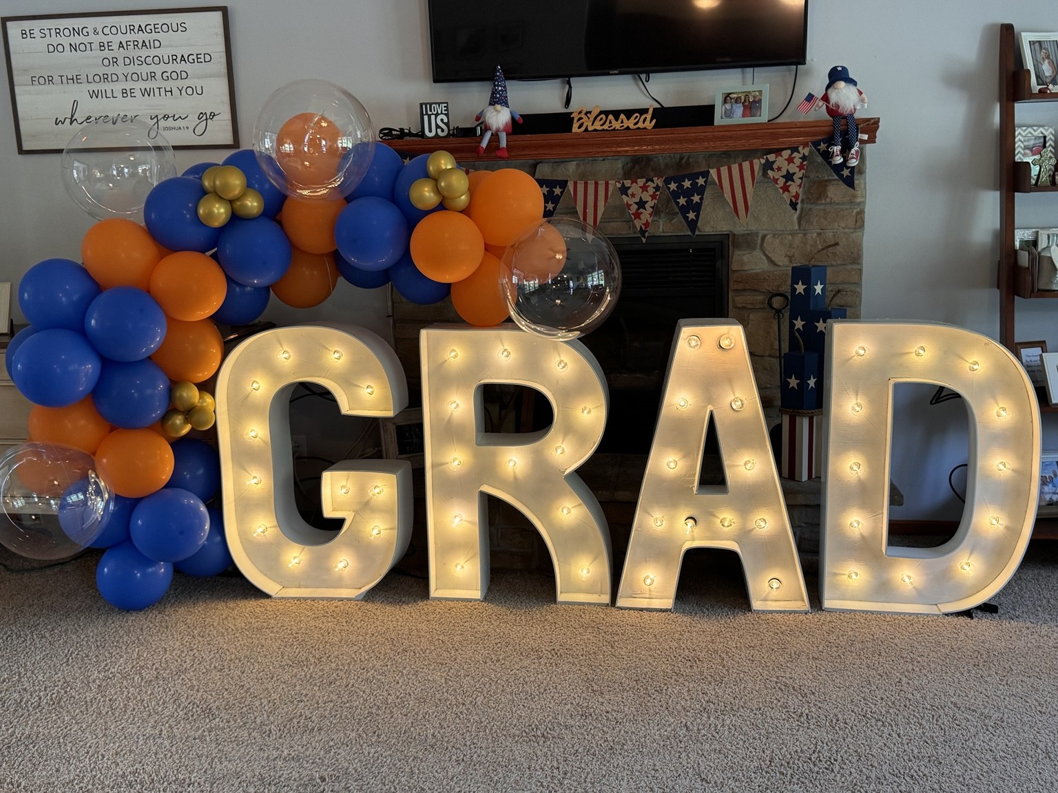 Illuminated GRAD marquee letters with blue and orange balloons