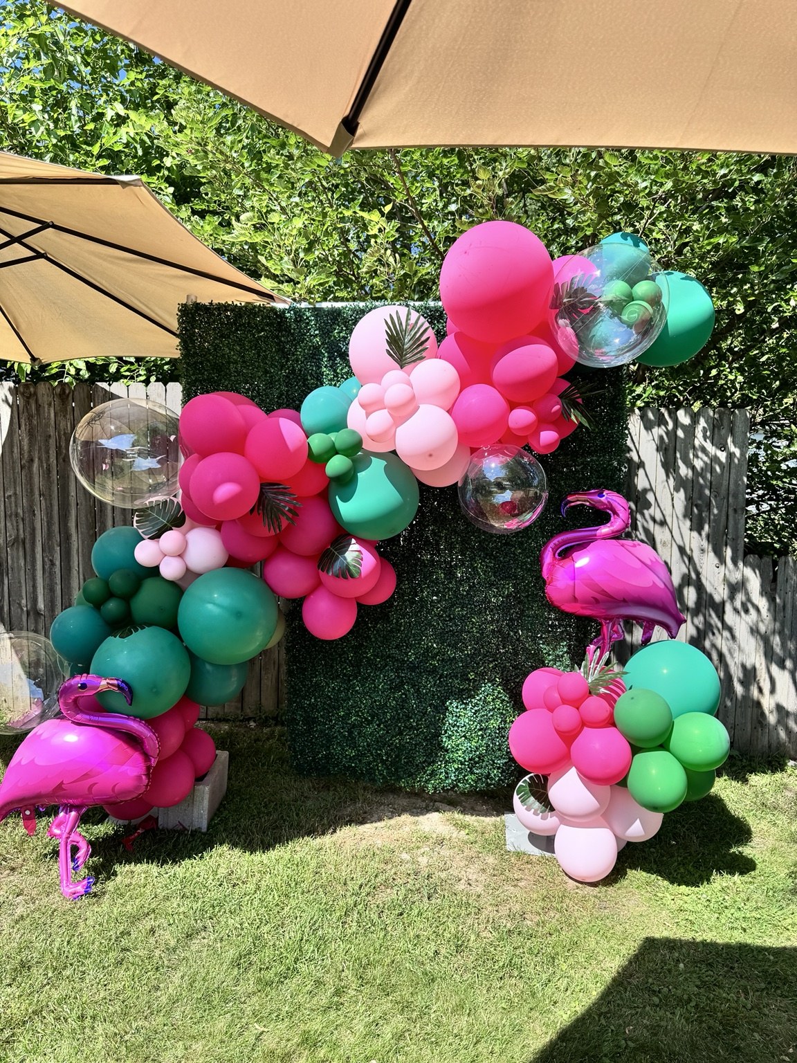 Outdoor tropical balloon backdrop with pink flamingos and pink and green balloons