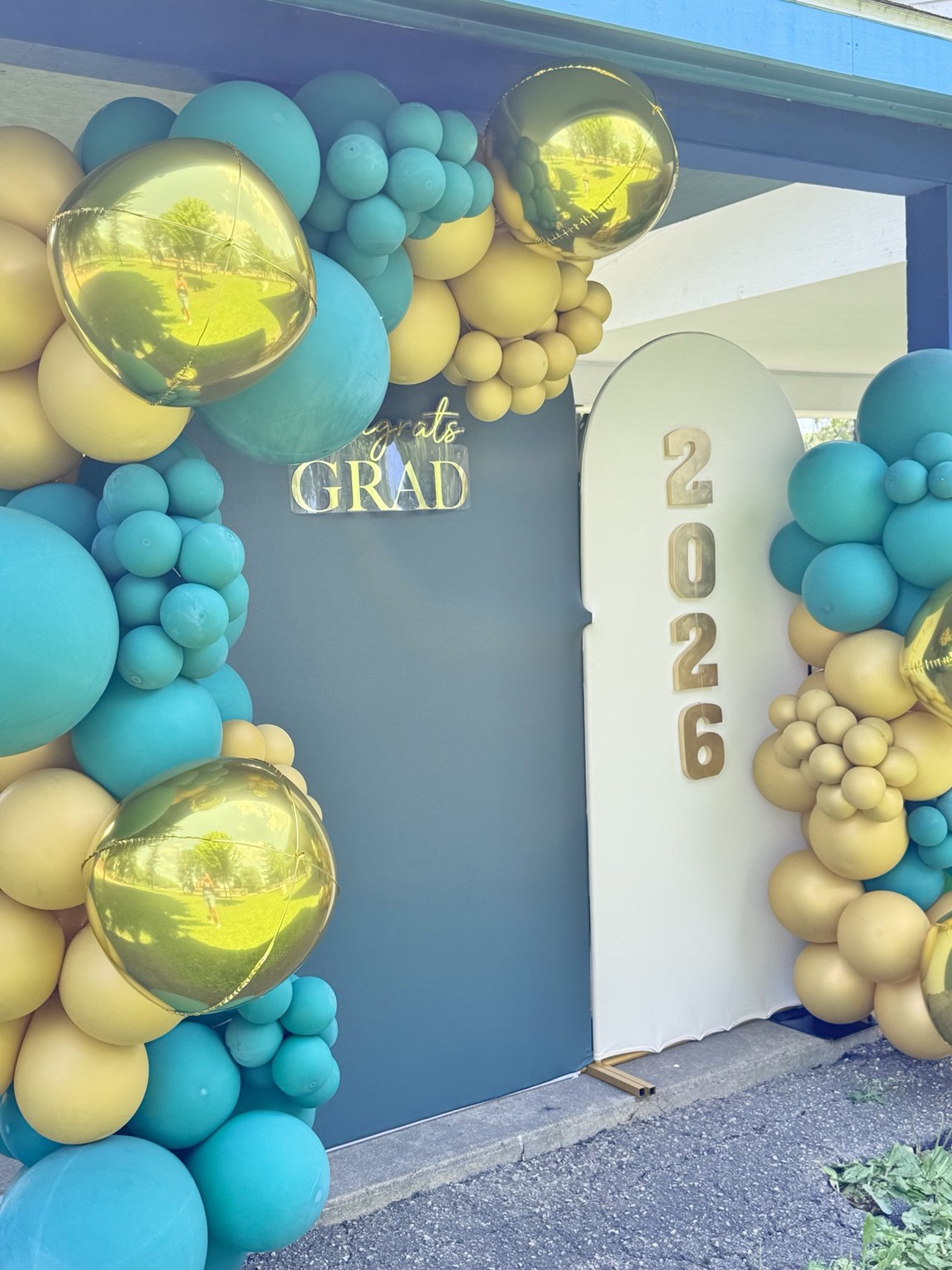 Teal and gold graduation balloon backdrop with illuminated 2026 display