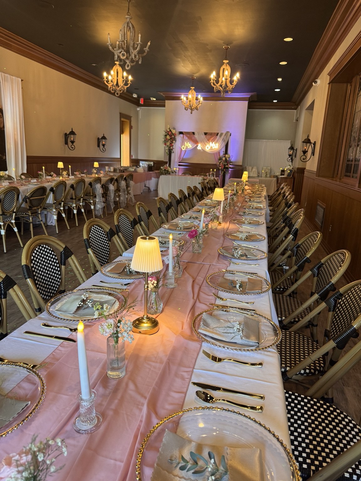 Long wedding reception table with blush runner, candles and floral accents