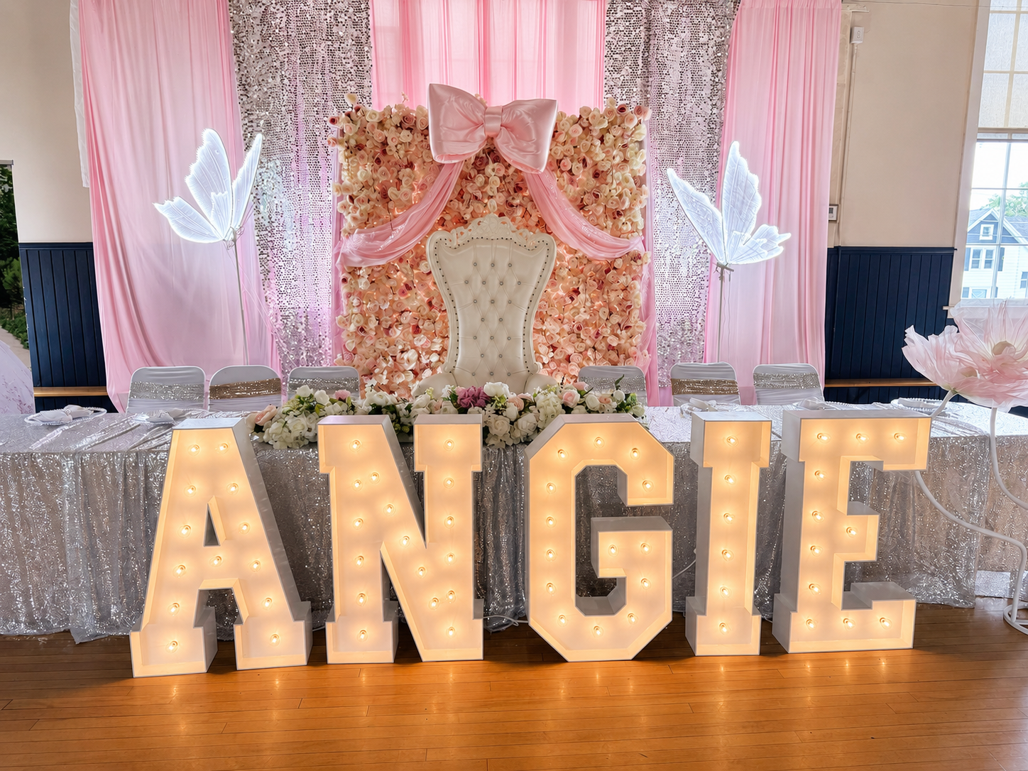 Pink and rose-gold quinceañera stage with a throne, draping and lit marquee letters