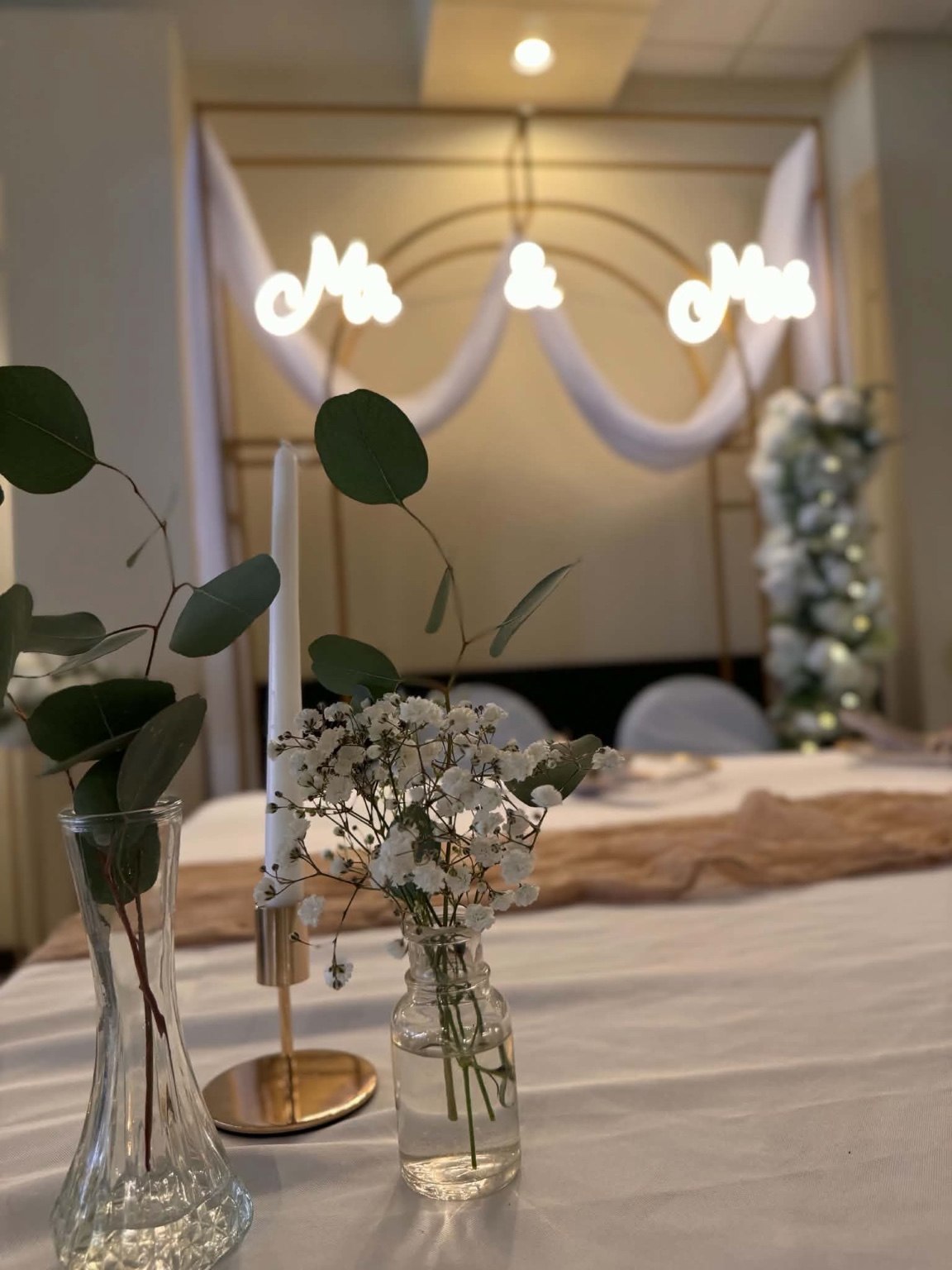 Bud vases and gold candle holders with a draped sweetheart backdrop