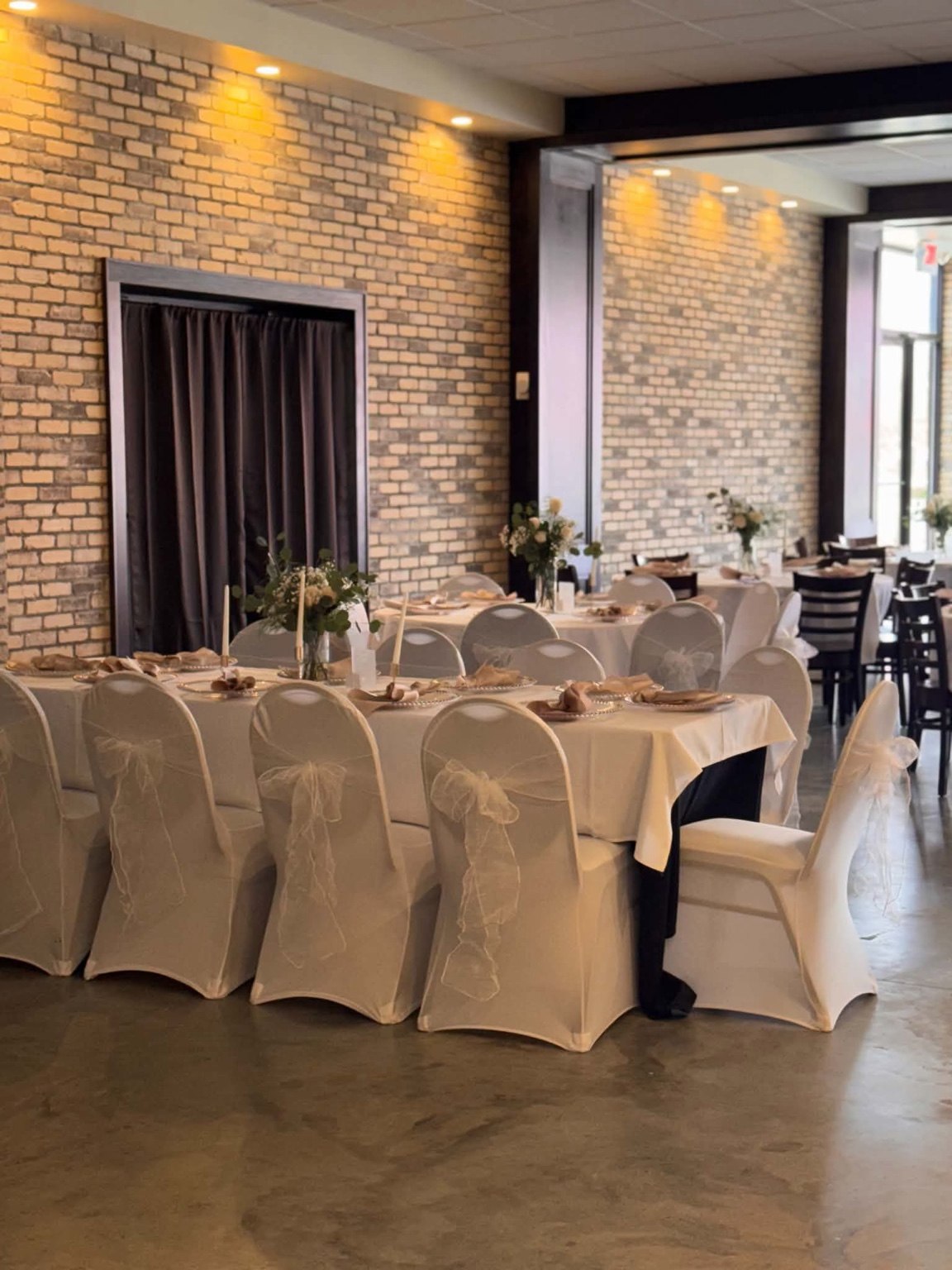 Wedding reception with white chair covers, neutral linens and floral centerpieces